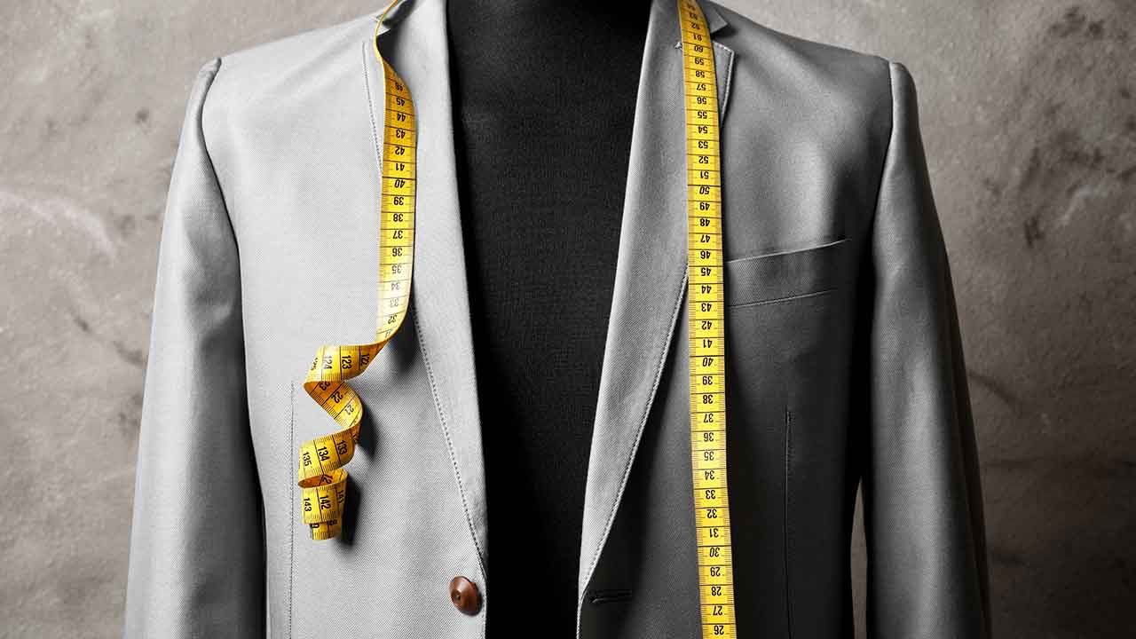 A mannequin wearing a suit with a measuring tape.